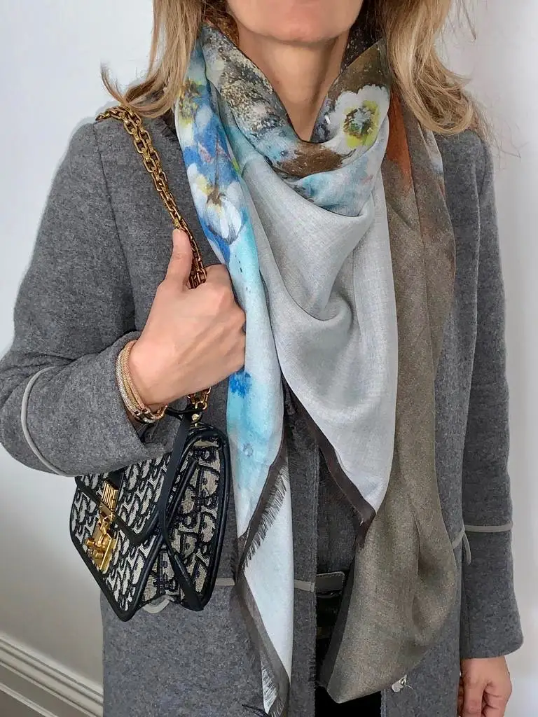 Woman wearing gray coat and patterned scarf.