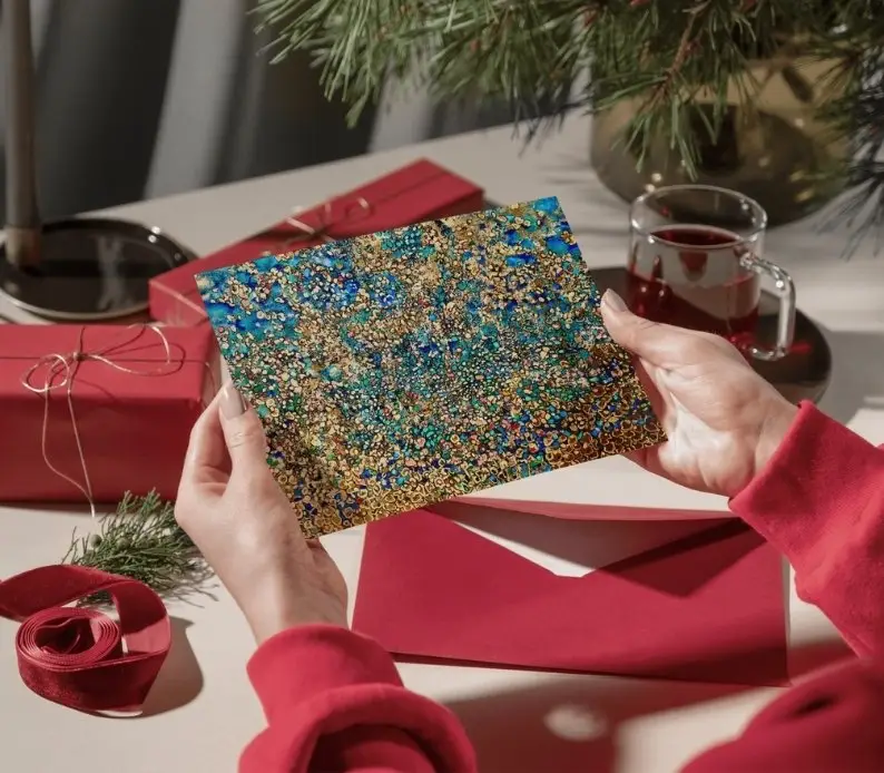 Person holding decorative card and red envelope.