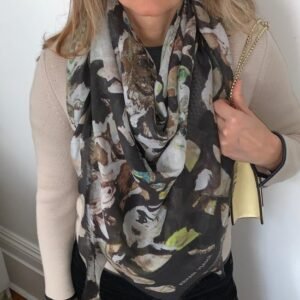 Woman wearing printed scarf holding beige bag.