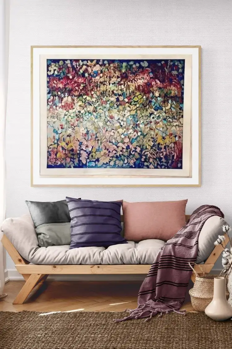 Abstract floral painting above cozy sofa with cushions.