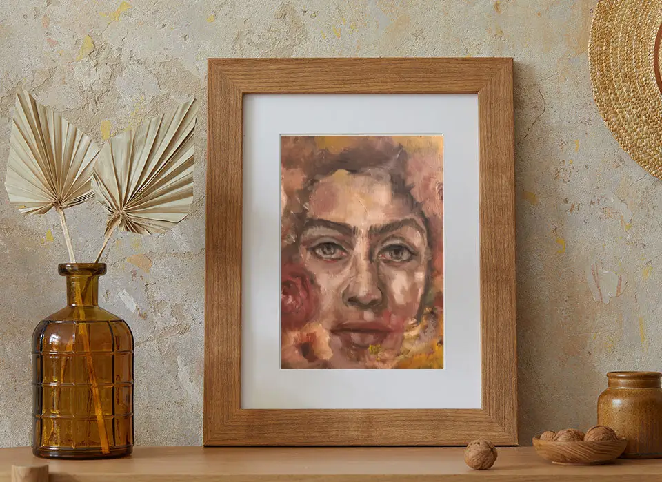 Framed abstract portrait on textured wall, vase nearby.